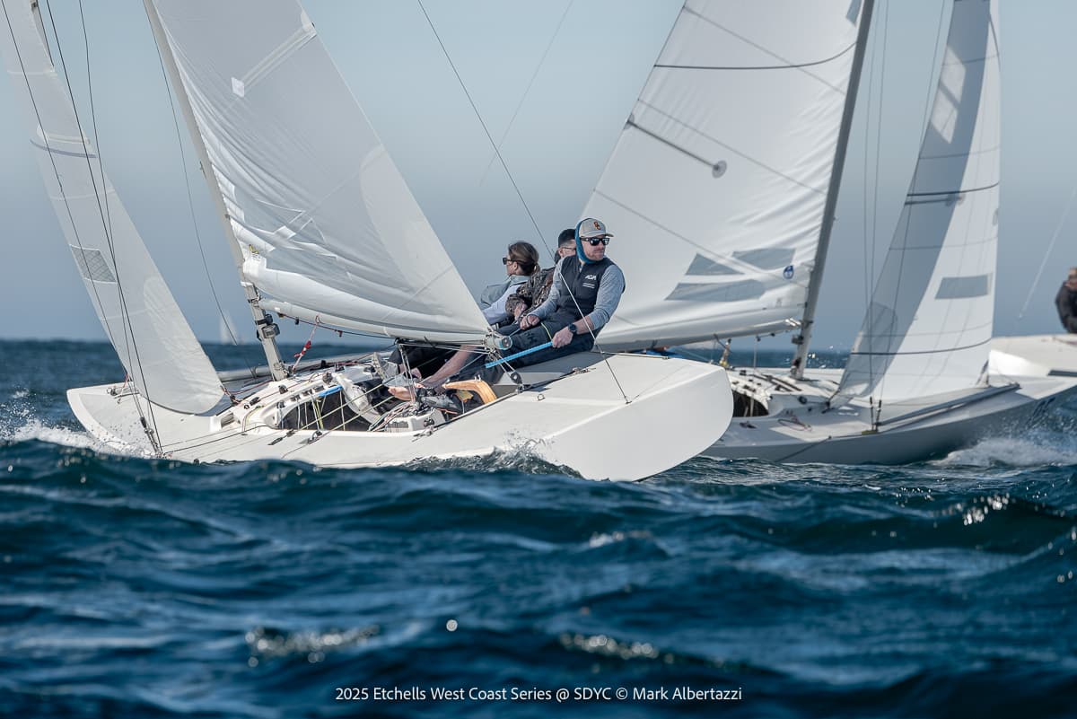 Two white sailboats racing on choppy dark blue water